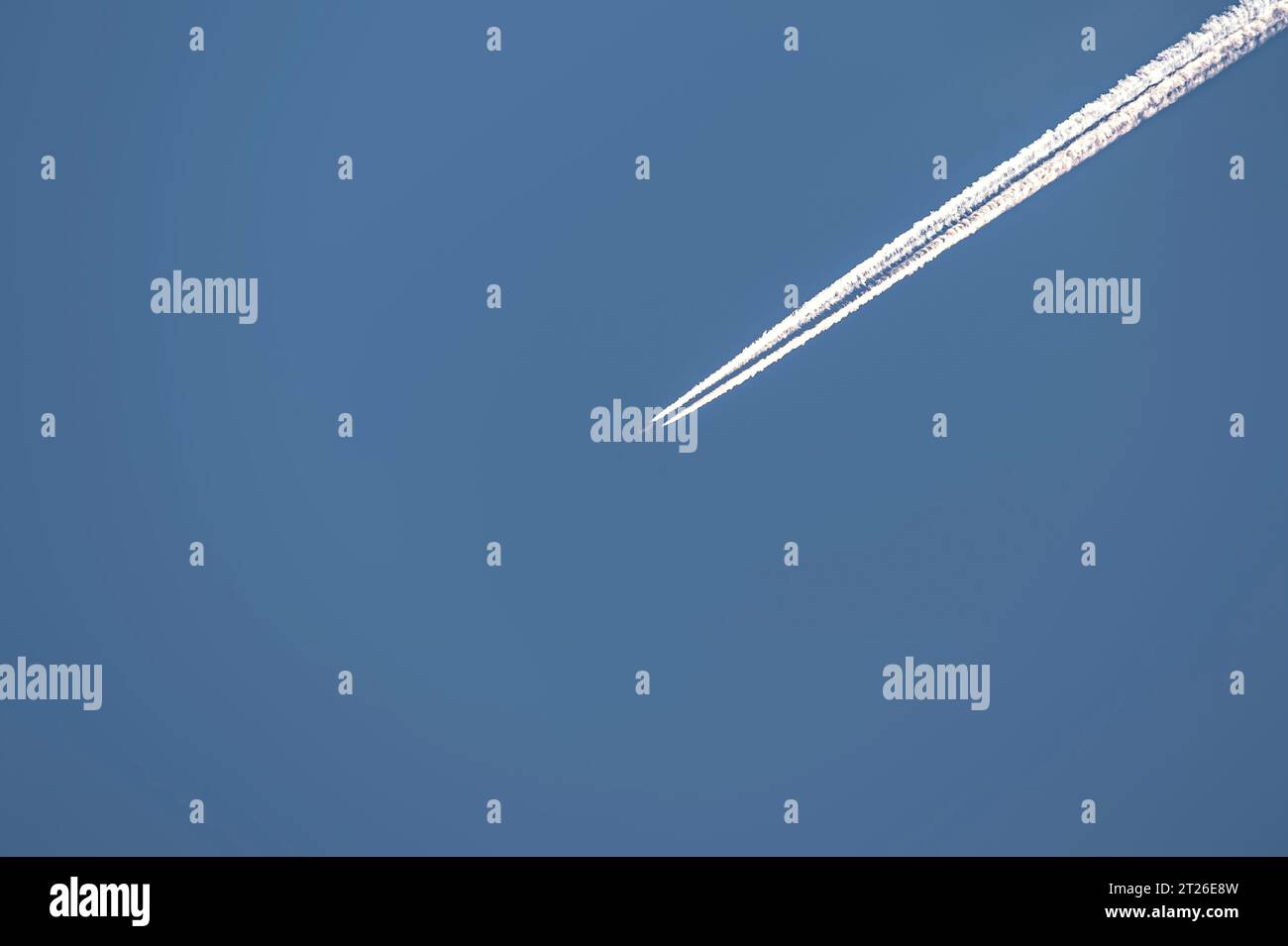 Plane flying through a clear blue sky leaving a long trail behind Stock ...