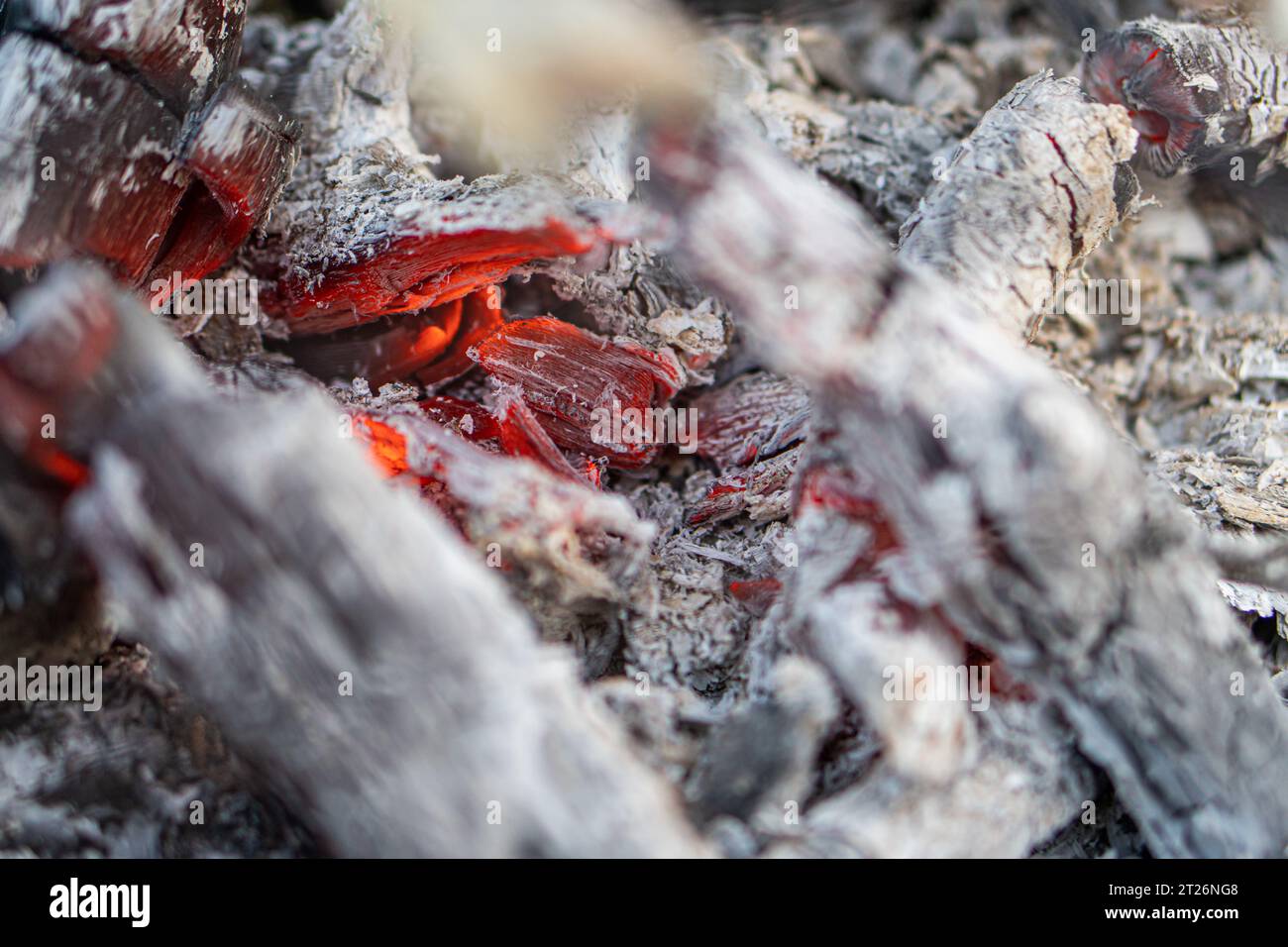 Dark black background of burnt wood with red hot embers still burning. Stock Photo