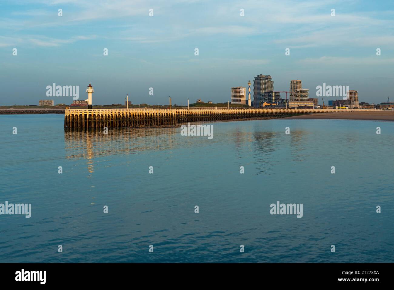 Pier and lighthouse with modern apartment buildings at sunset, Oostende, West Flanders, Belgium. Stock Photo