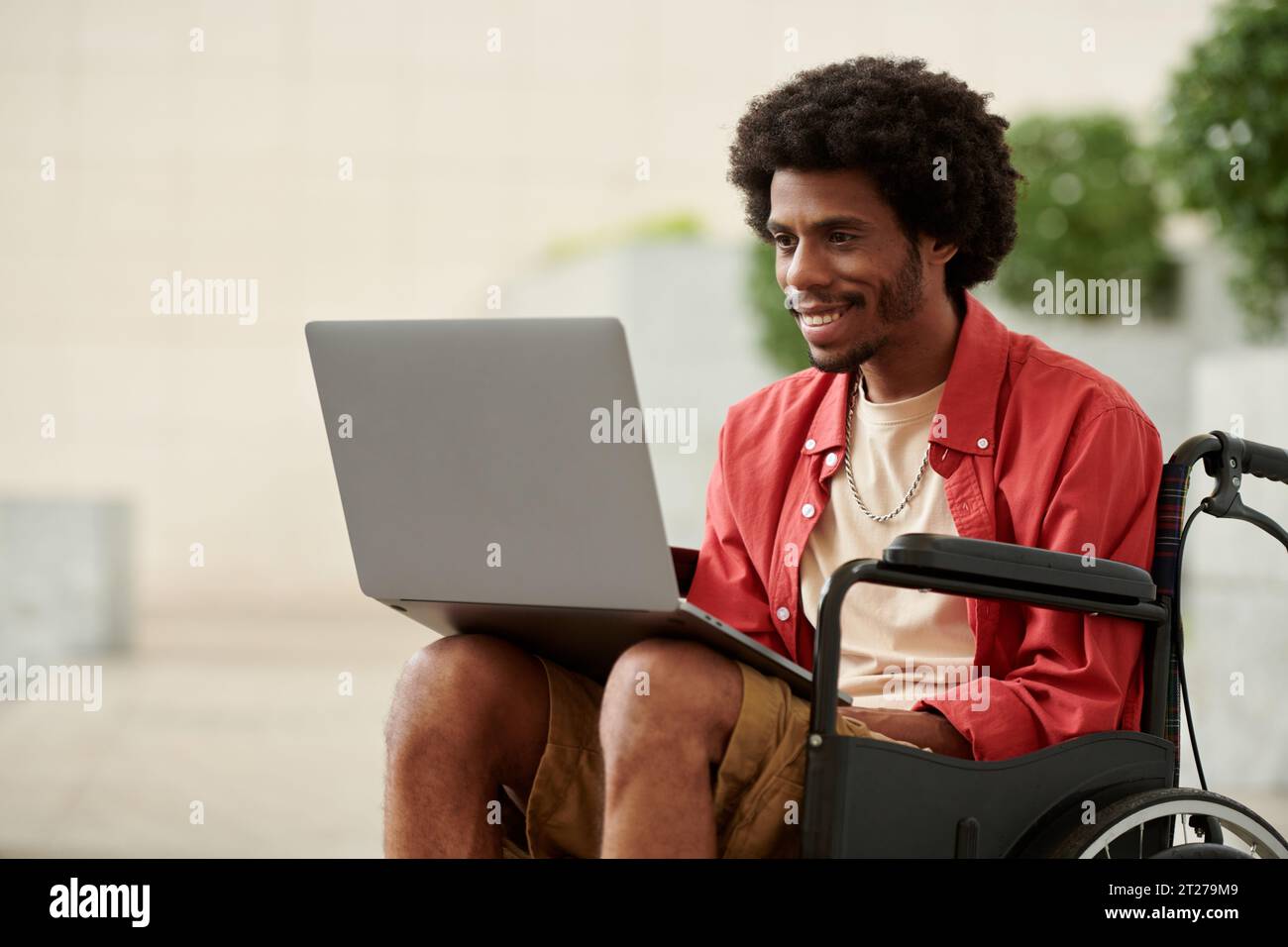 Smiling Black man with disability working on laptop Stock Photo
