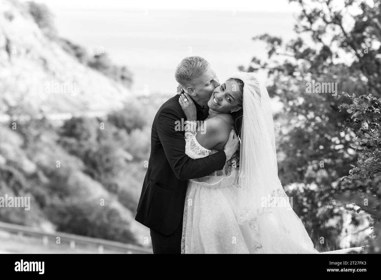 Happy newlyweds kiss passionately against the backdrop of a beautiful ...