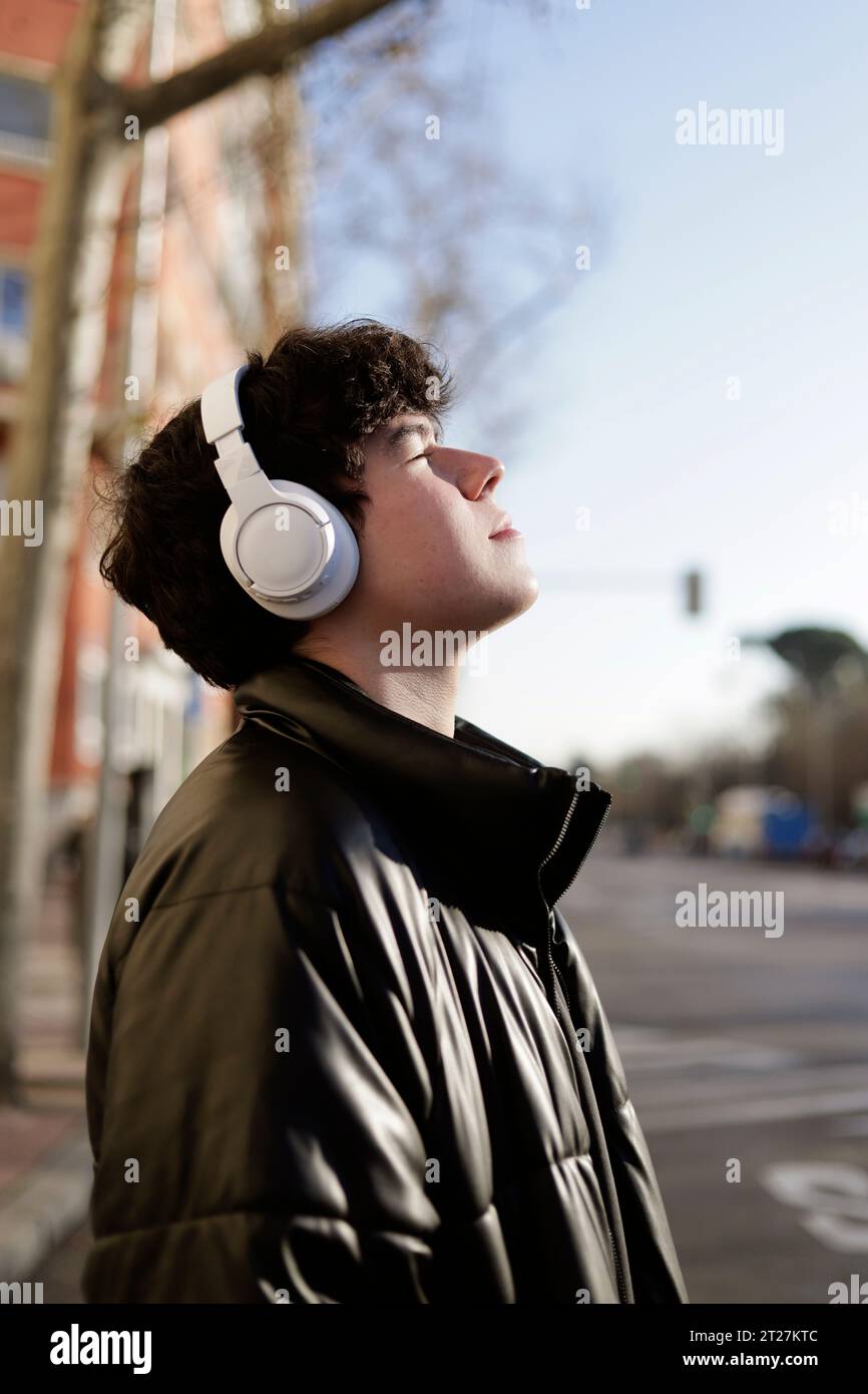 guy with headphones and eyes closed in winter with face to the sun Stock Photo