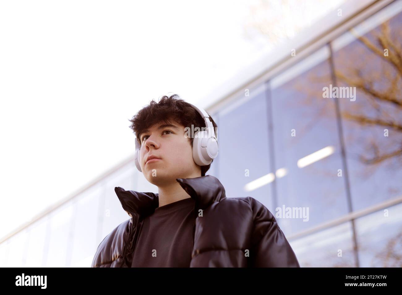 photo from below of boy with headphones outdoors Stock Photo