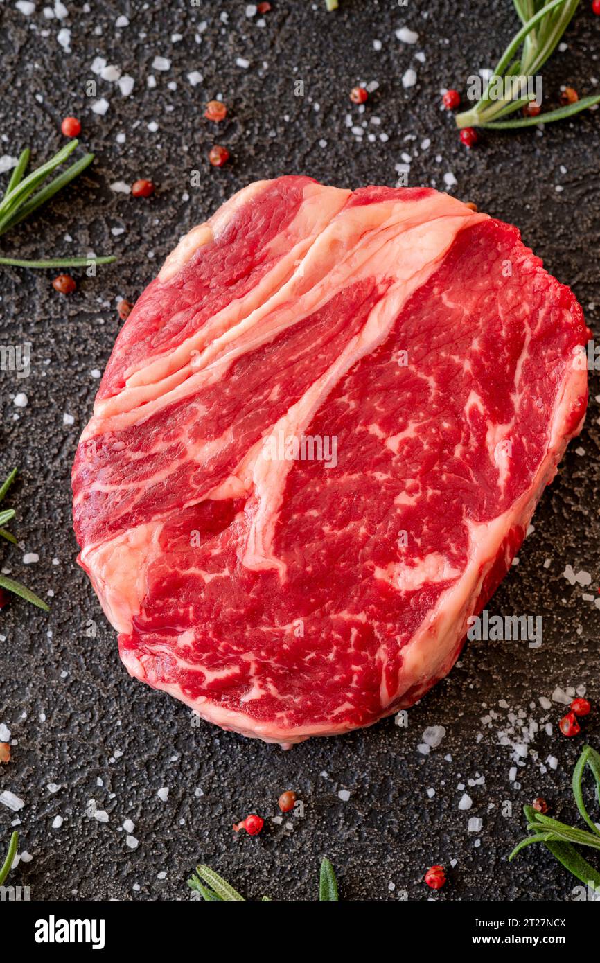 Uncooked rib eye beef steak on the black background Stock Photo