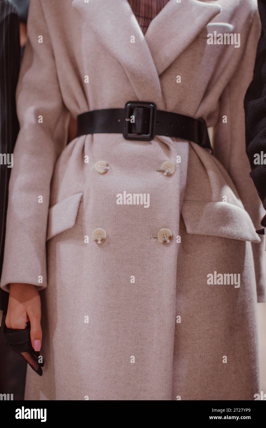 Black leather belt and a beige long coat. Women's fashion and stylish accessories. Autumn winter fashion details Stock Photo