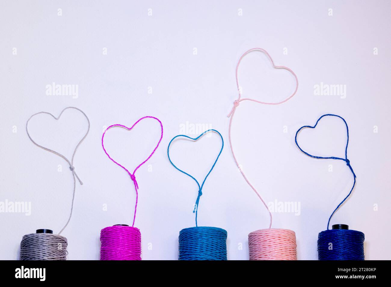 Conceptual art made with threads that form hearts on a light background. Stock Photo