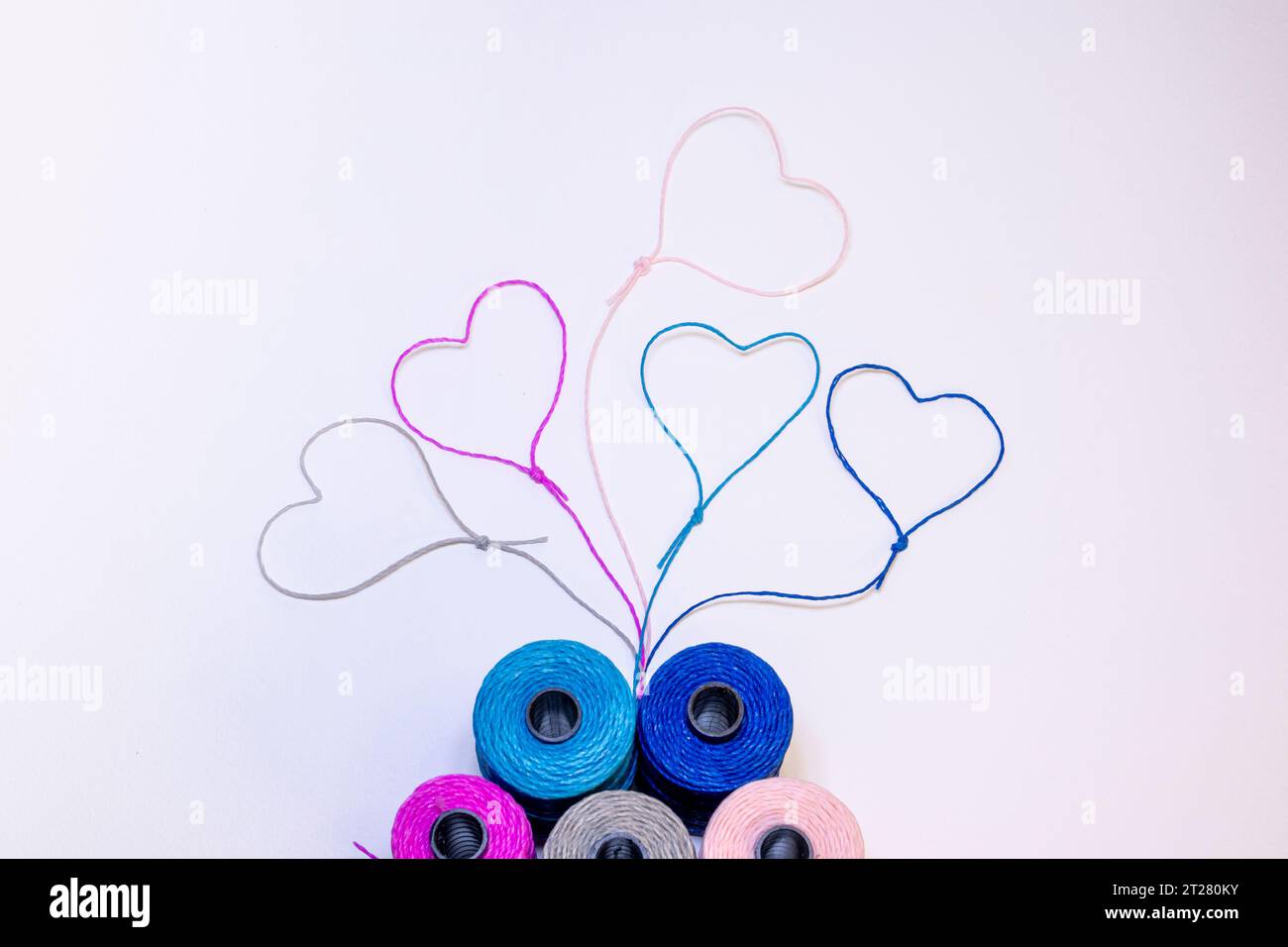 Conceptual art made with threads that form hearts on a light background. Stock Photo