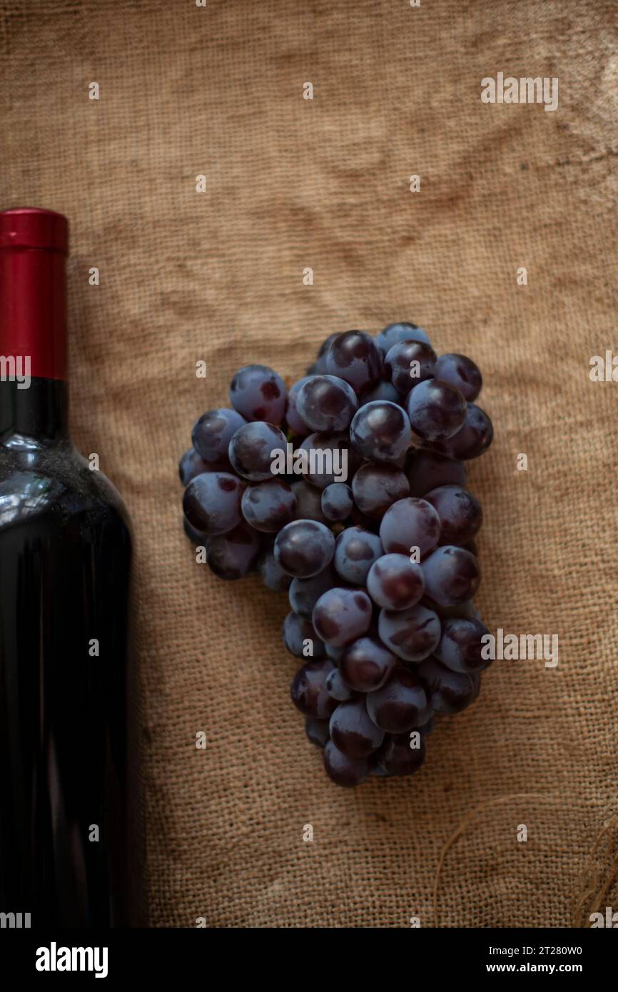 Moldovan wine. Bunch of grapes and a bottle of red wine on burlap. View from above. Copy space. Stock Photo