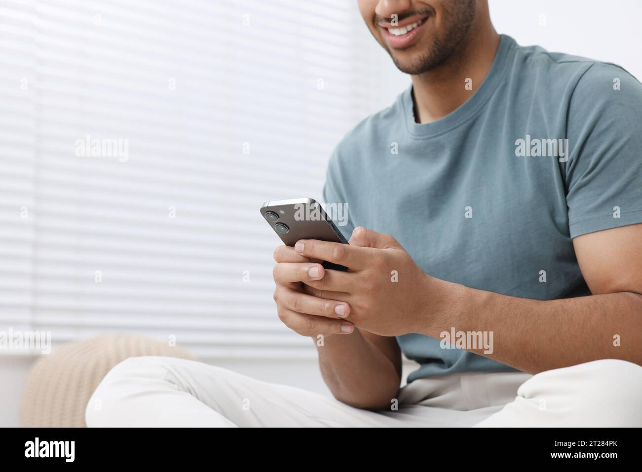 Man using modern mobile phone indoors, closeup. Space for text Stock Photo