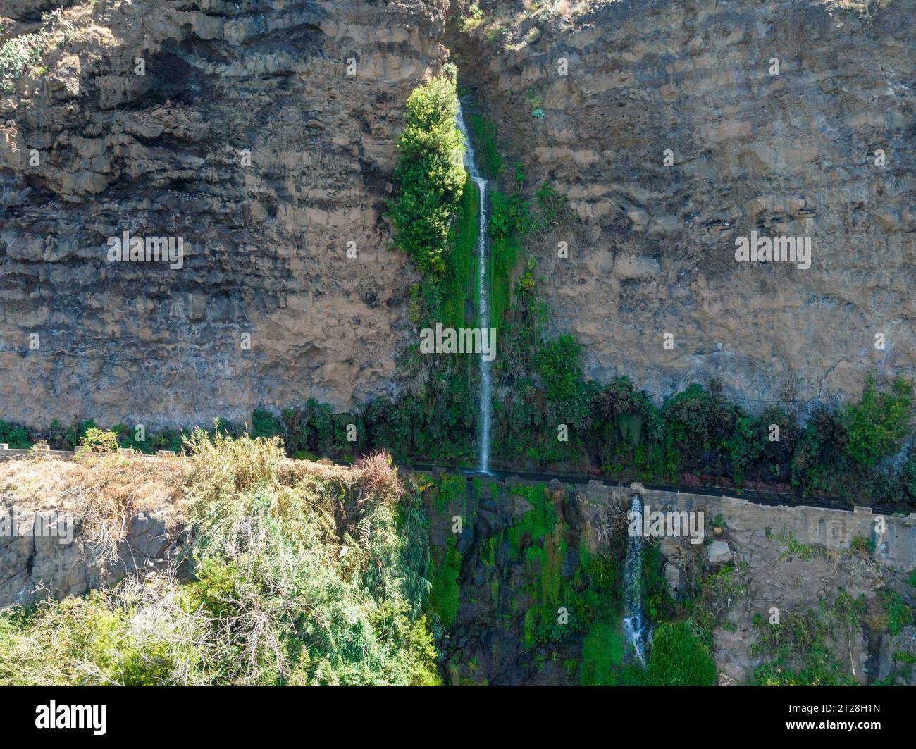 Aerial drone view of Angels waterfall (Cascata dos Anjos) in Madeira island. The waterfall cascades over the rockface onto the regional roadway, and s Stock Photo