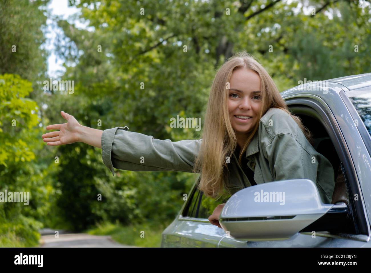 Blonde woman sticking head out of windshield car. Young tourist explore local travel making candid real moments. True emotions expressions of getting away and refresh relax on open clean air Stock Photo