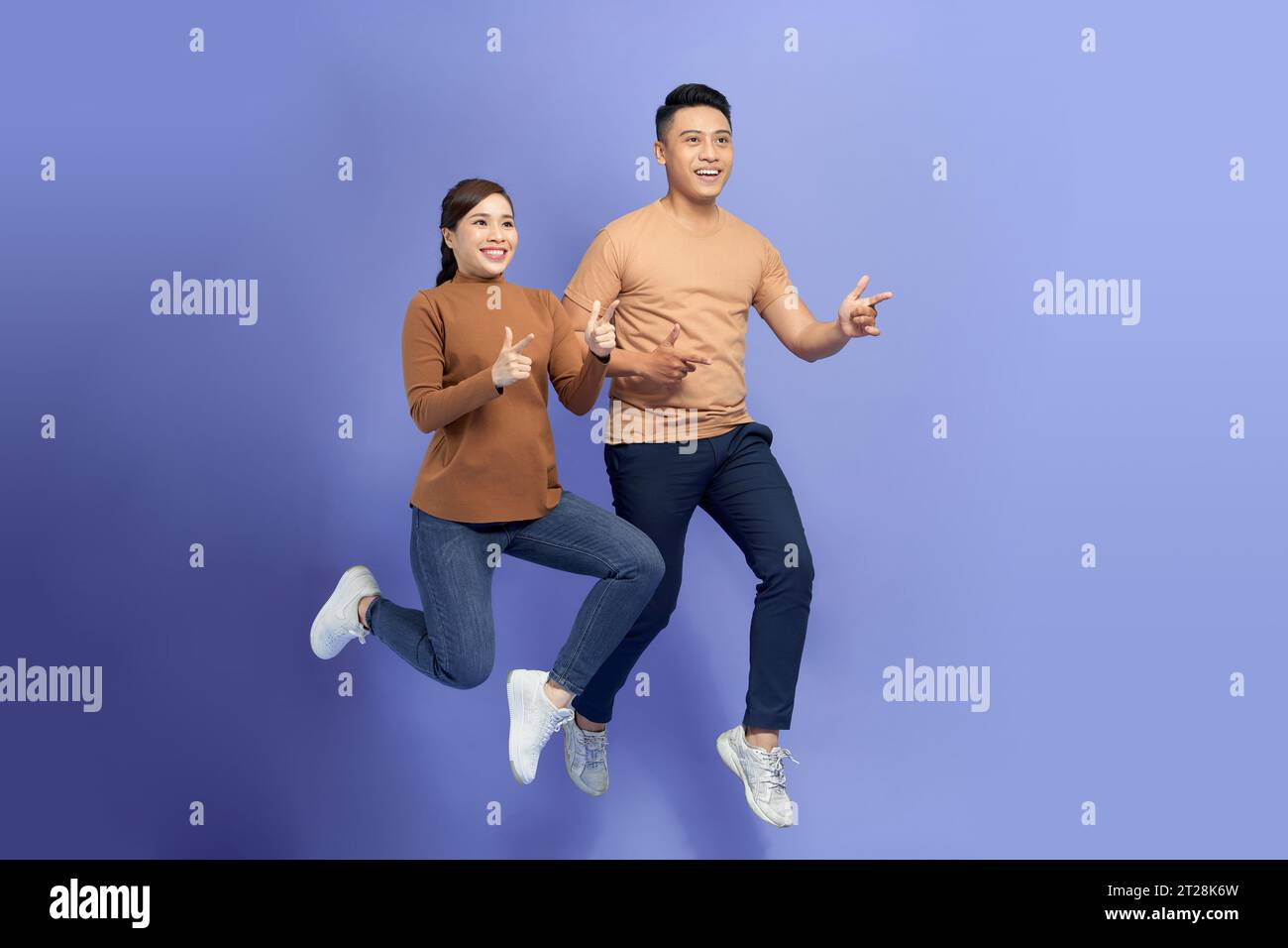 Happy Asian couple love excited smiling with thumb up gesture isolated on violet Stock Photo
