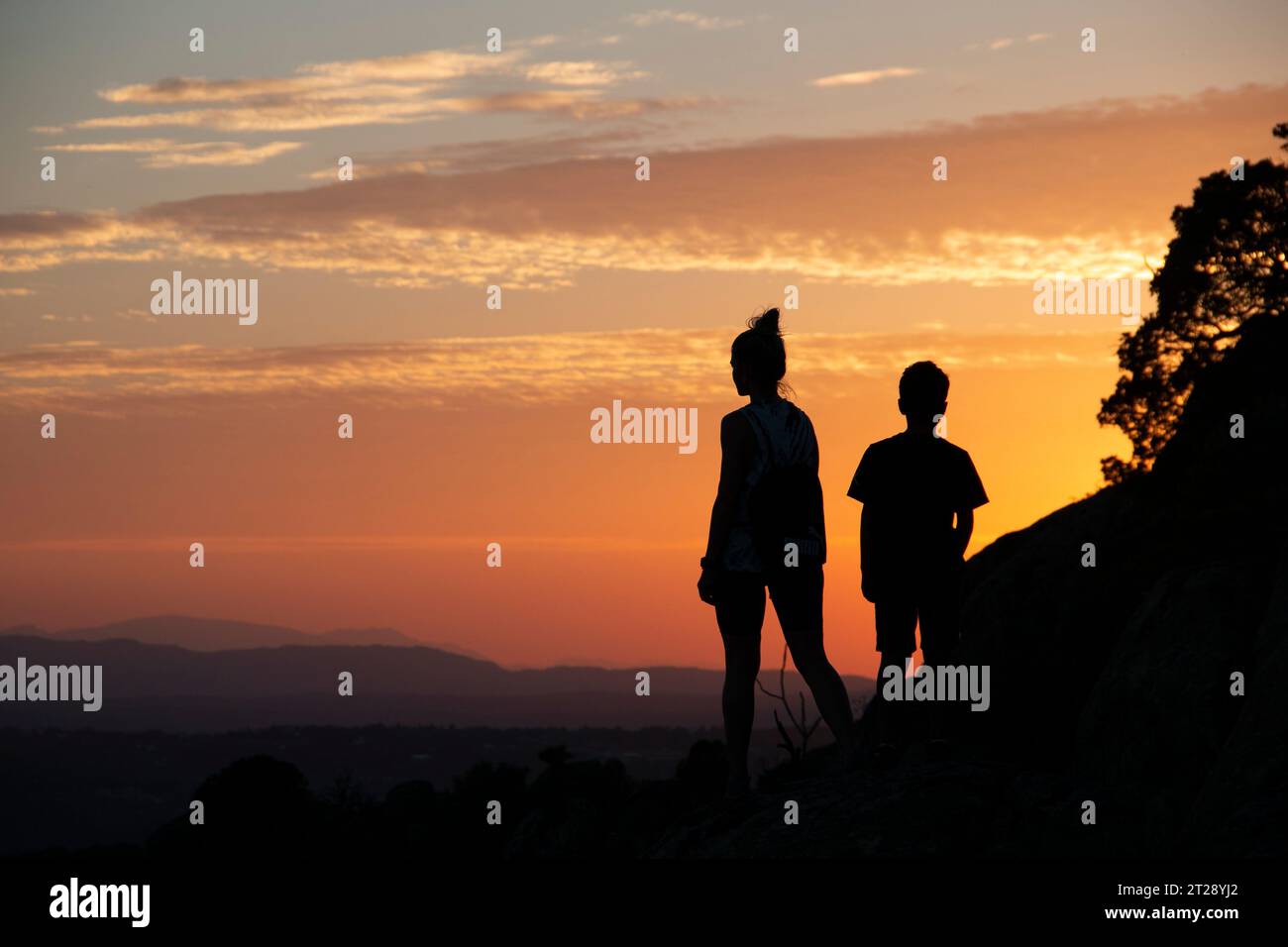 Silhouettes of a single-parent family on a sunset in the mountains Stock Photo