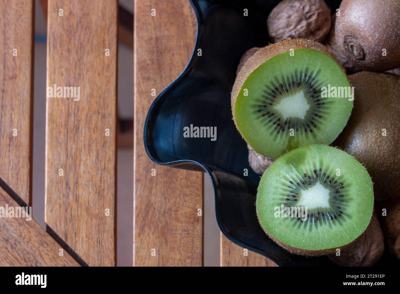 https://c8.alamy.com/comp/2T291EP/kiwis-in-a-fruit-bowl-made-of-a-vinyl-disc-on-a-wooden-table-in-overhead-view-2T291EP.jpg