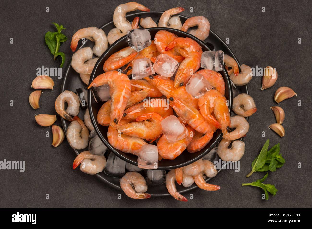 Tiger prawns and shrimp in black plate with ice. Black background