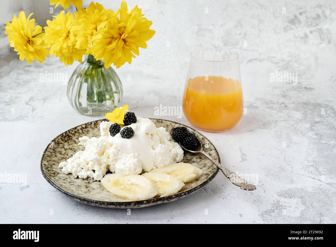 Farm fresh cottage cheese with berries and banana slices. Early breakfast of cottage cheese with fruit and natural juice. Stock Photo