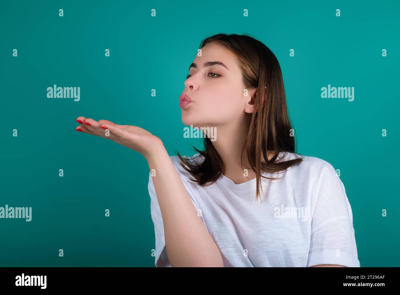 Blowing lips sending sweet air kiss. Lovely girl sending blowing kiss with pout lips isolated on studio background. Affection feelings. Portrait Stock Photo