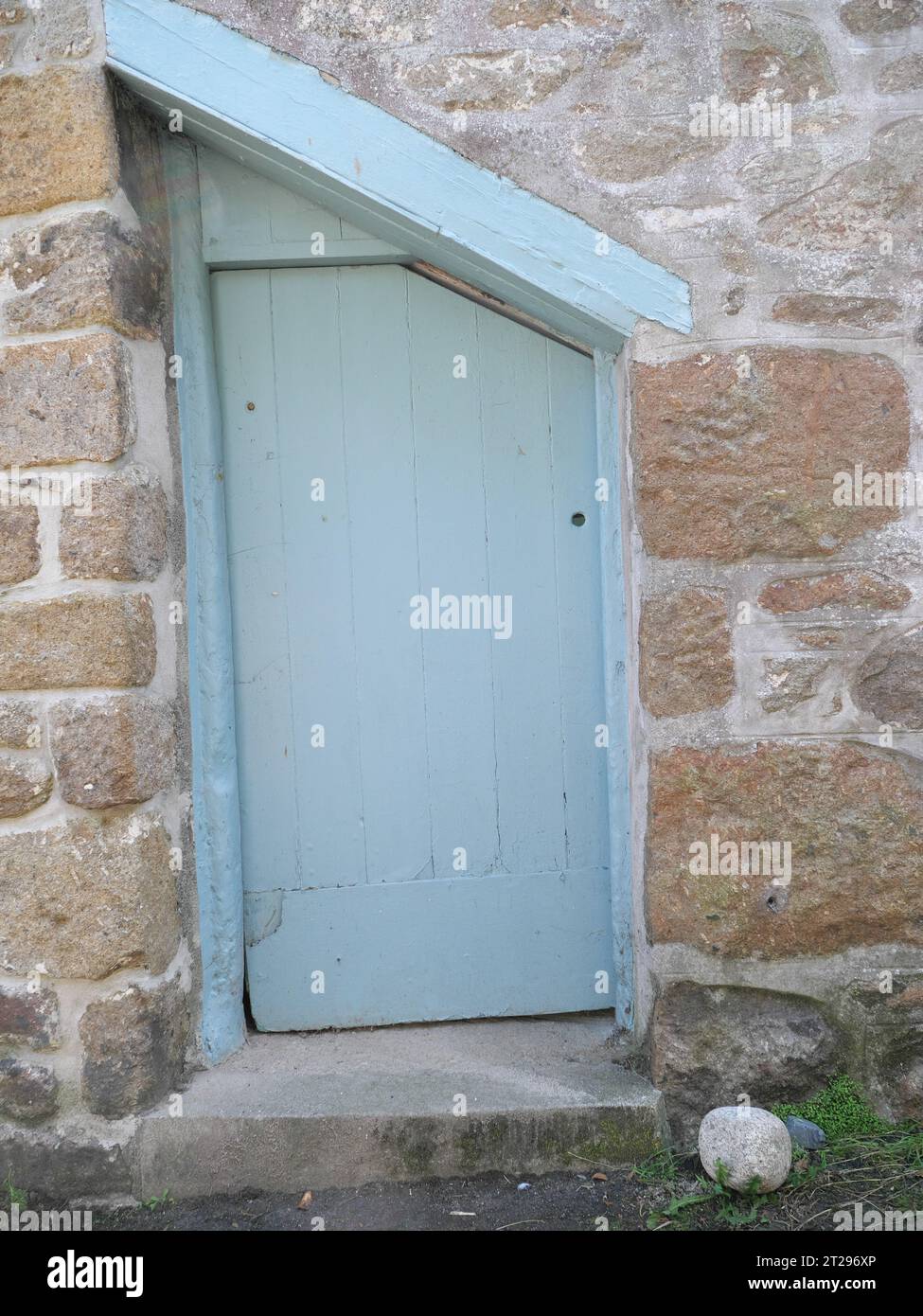 Green slanting roofed door on fieldstone house in Mousehole in Cornwall England Stock Photo