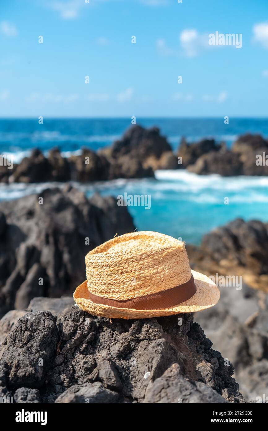 Hat next to a natural pool in summer, coastal town of Porto Moniz, Madeira. Vertical photo, lifestyle Stock Photo