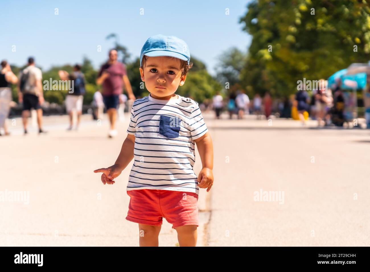 Portrait of a one year old Caucasian boy looking at the camera walking in a park with a cap Stock Photo
