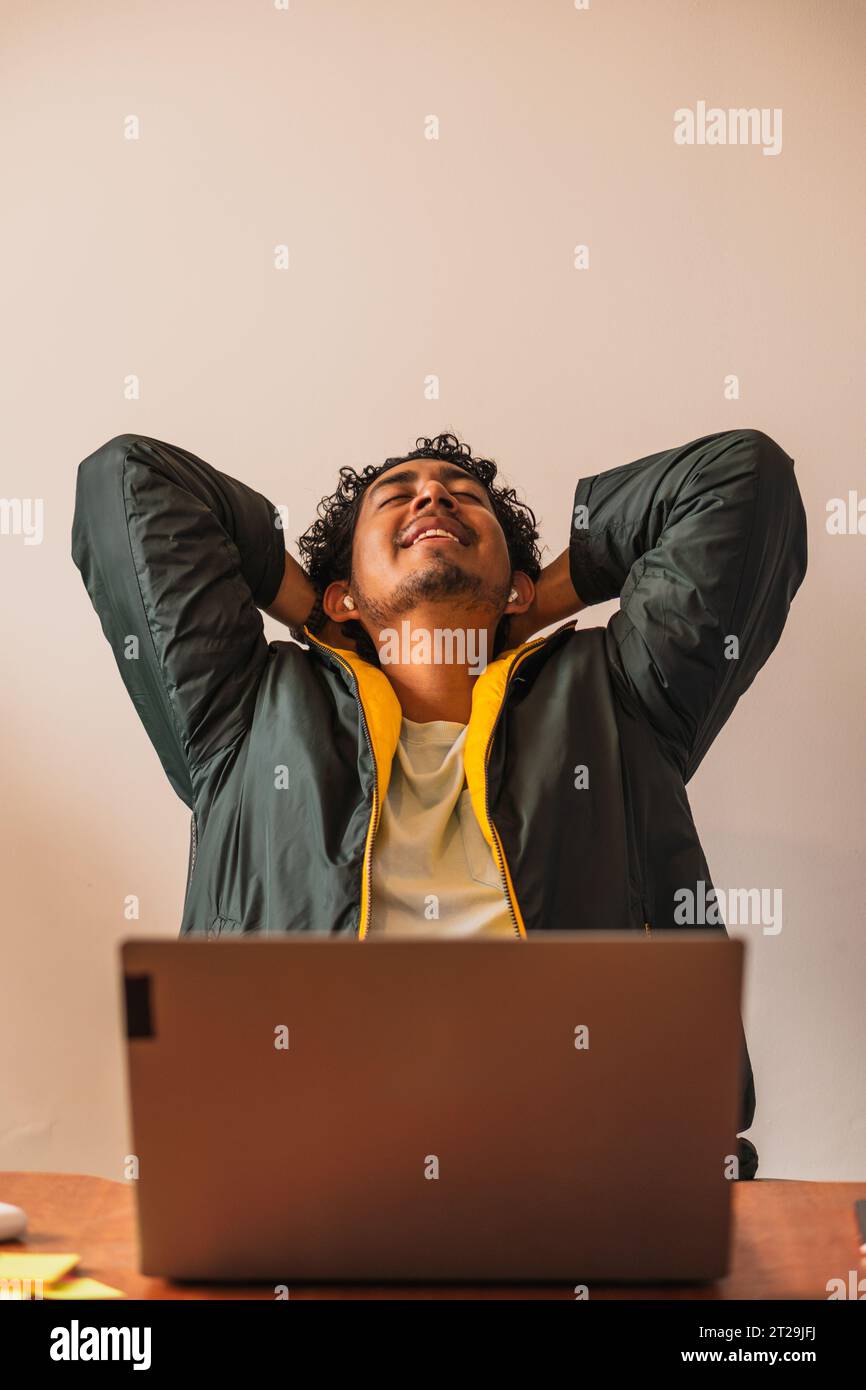 Positive male remote worker using netbook for online project while working on hoffice at table in blurred background Stock Photo