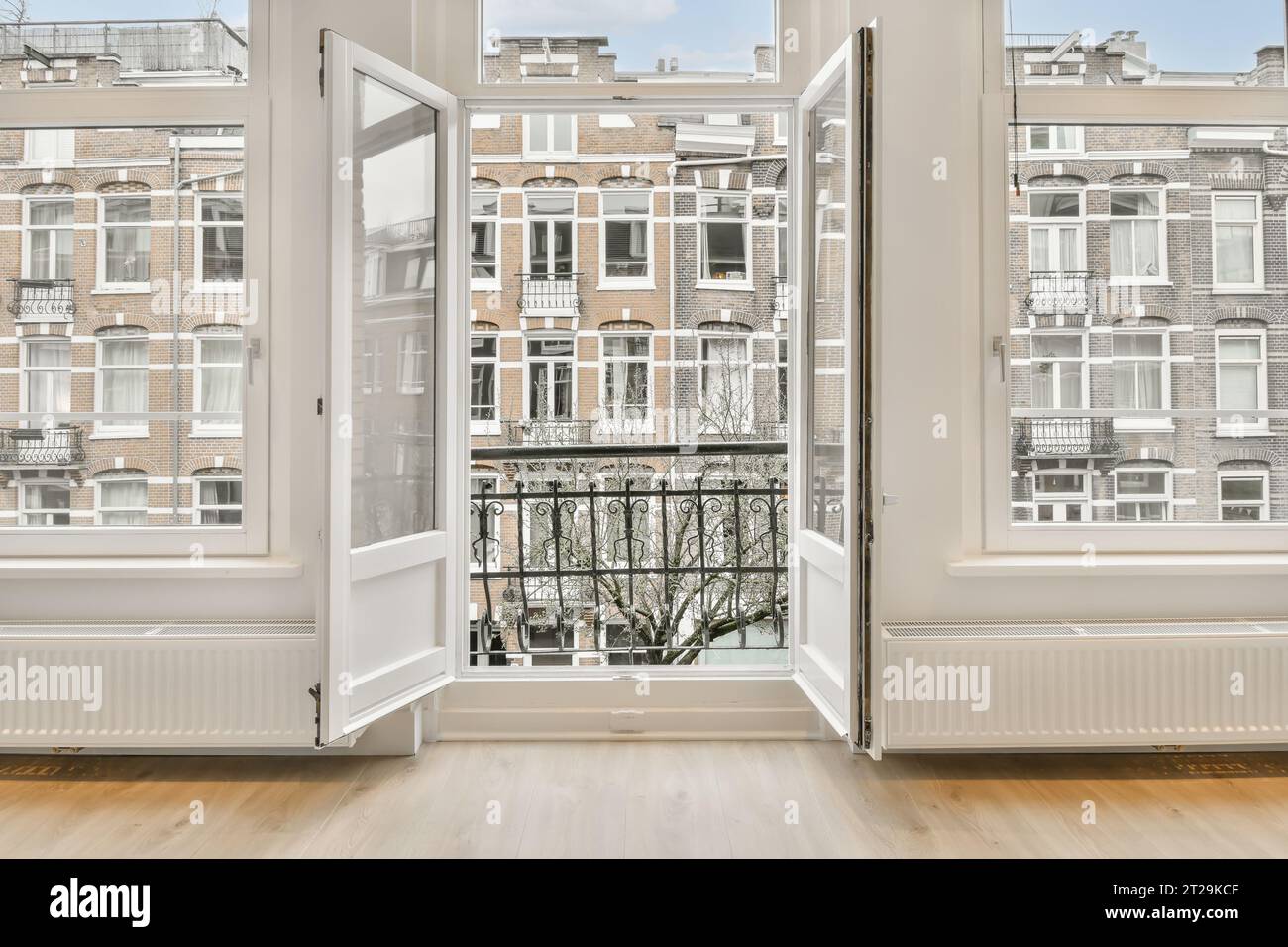 Residential buildings and balcony seen through open large window of new ...