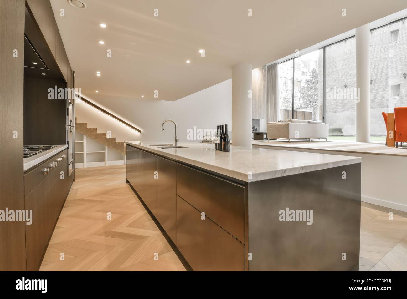 Interior of modern kitchen with large marble island and brown cabinets ...