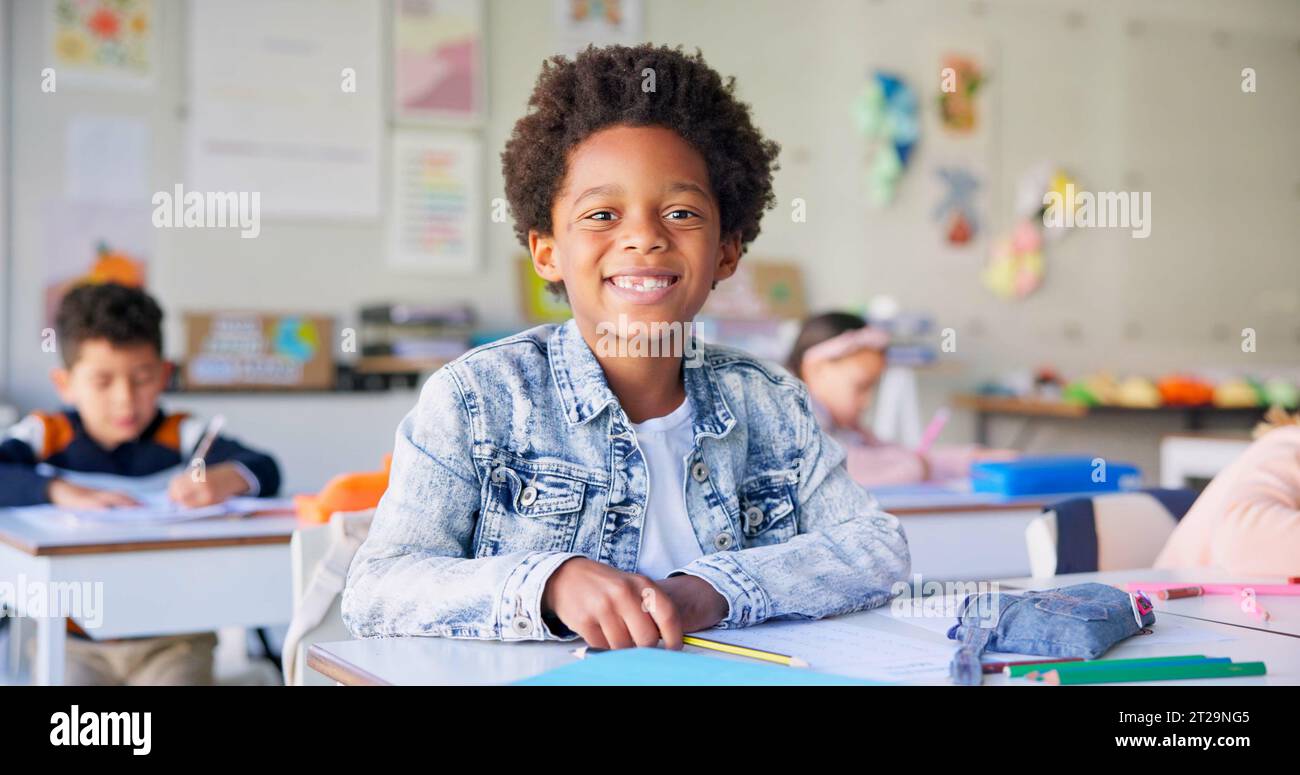 Smile, education and writing with boy in classroom for learning, knowledge and study. Scholarship, happy and future with portrait of young student at Stock Photo
