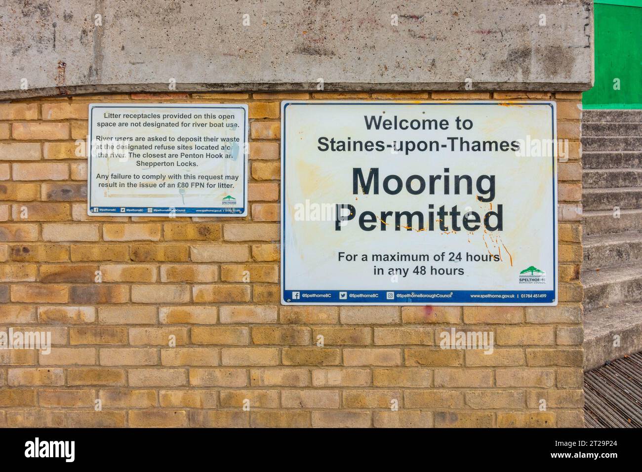Signs attached to a brick wall next to the River Thames at Stainesupon