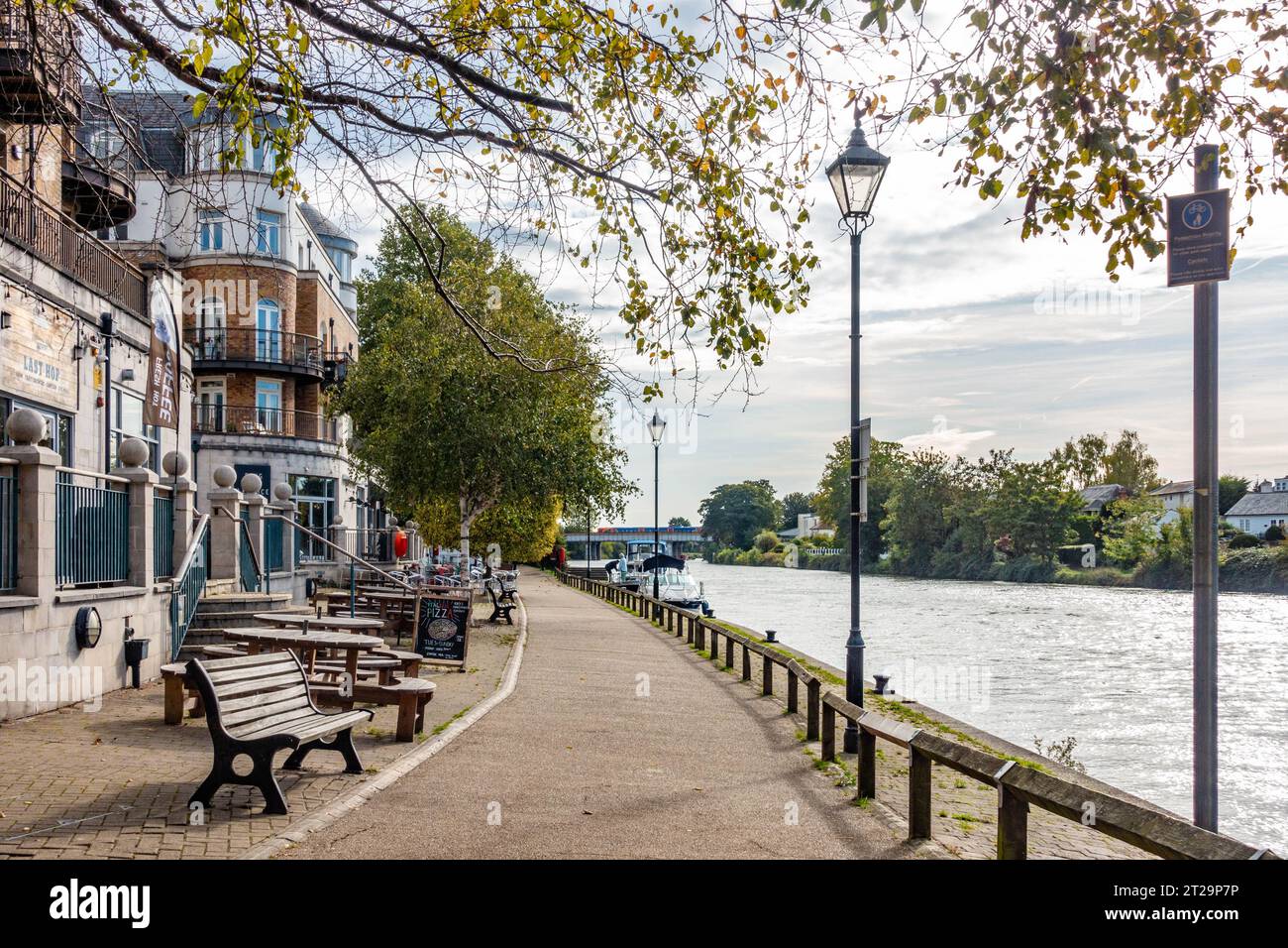 A view down The River Thames at Staines-upon-Thames past The Slug and Lettuce pub with tables and benches outside. Stock Photo