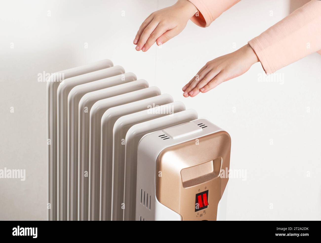Children's hands on the background of an oil electric heater on a white background. Concept for