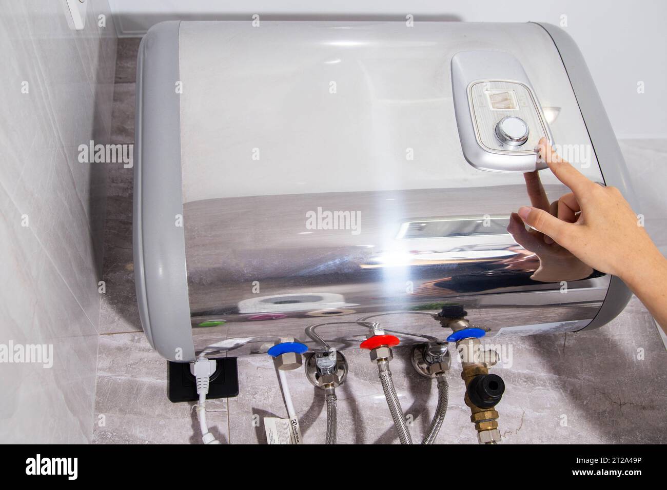 The girl regulates the temperature of water heating in the boiler in