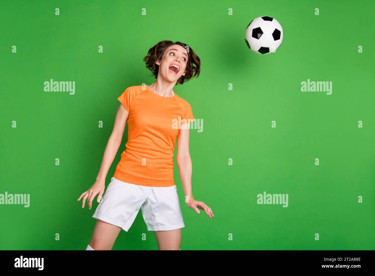 Photo of carefree astonished girl open mouth look flying ball head make shot isolated on green color background Stock Photo