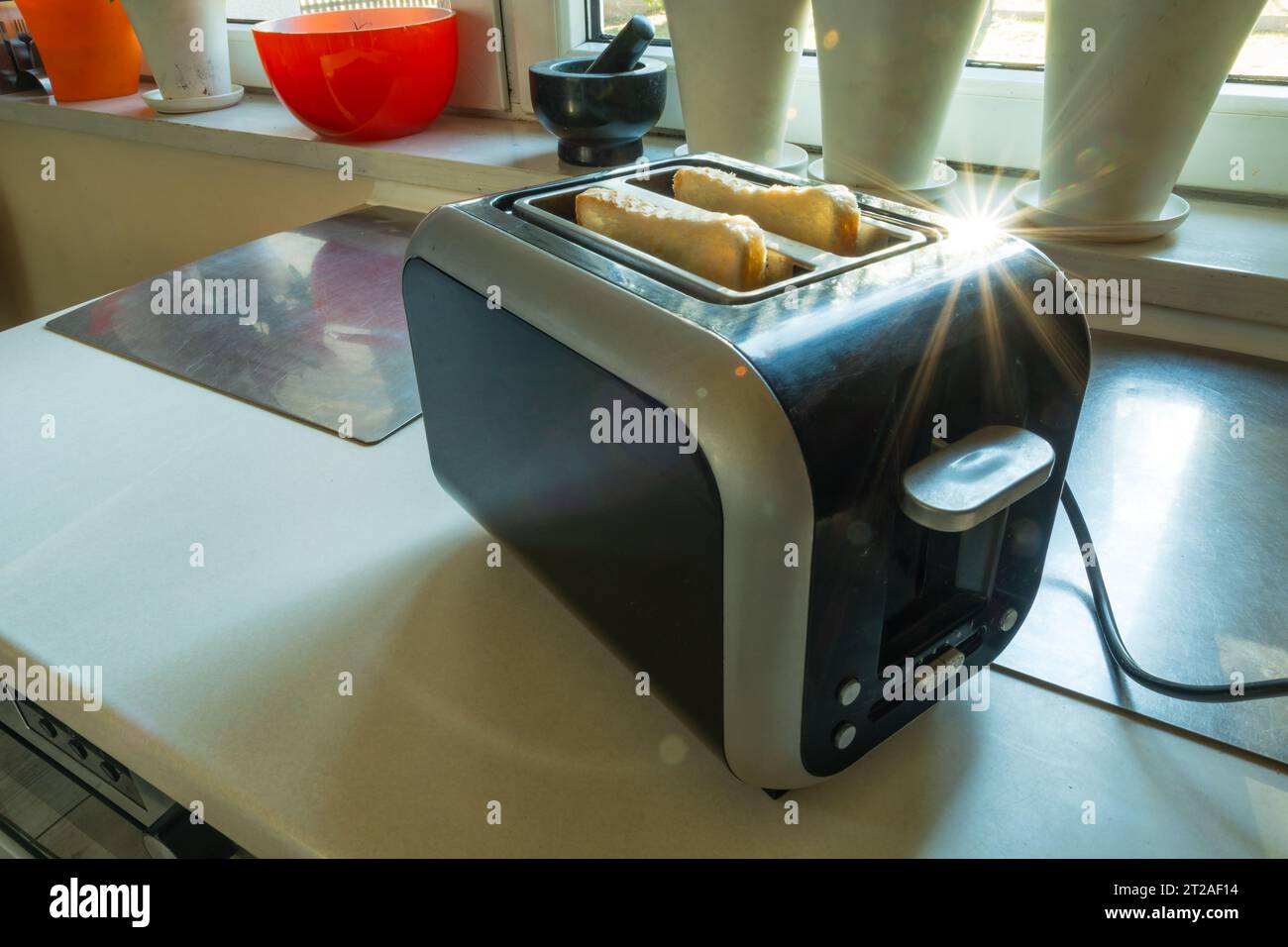 A toaster with slices of toast standing on the kitchen counter in sunny day Stock Photo