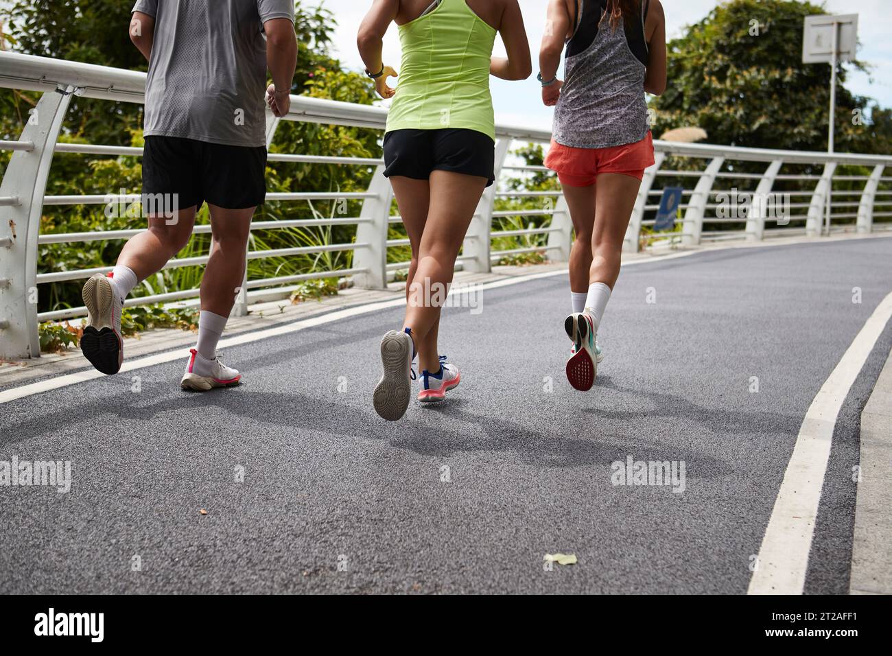 rear view of legs and feet of young asian people running outdoors in park Stock Photo