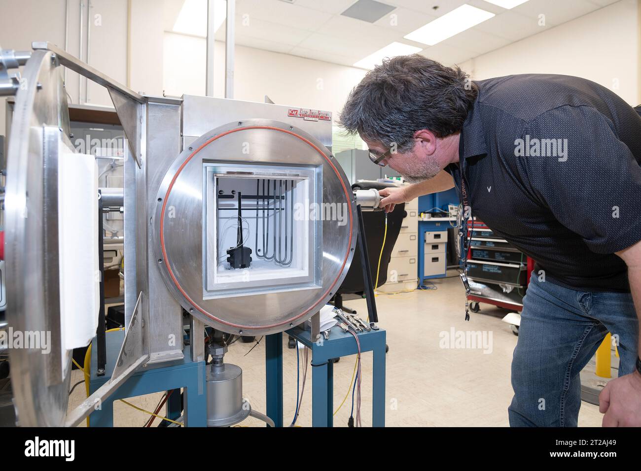 . Anthony piazza, a researcher at NASA’s Armstrong Flight Research center in Edwards, California, works with high-temperature strain sensors. This test article is a bending load bar, which enables high-temperature optical strain sensor research up to 1,800 degrees Fahrenheit. Stock Photo