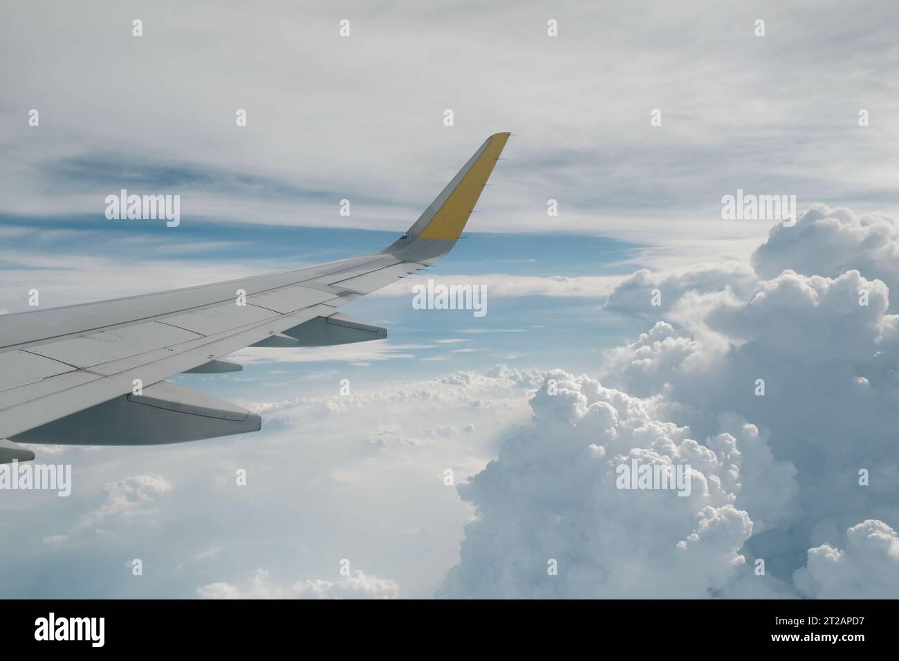 View of right wing from window of airplane flying up in the air. Clouds in blue sky. Plane in flight. Aviation business. Airline travel background. Stock Photo