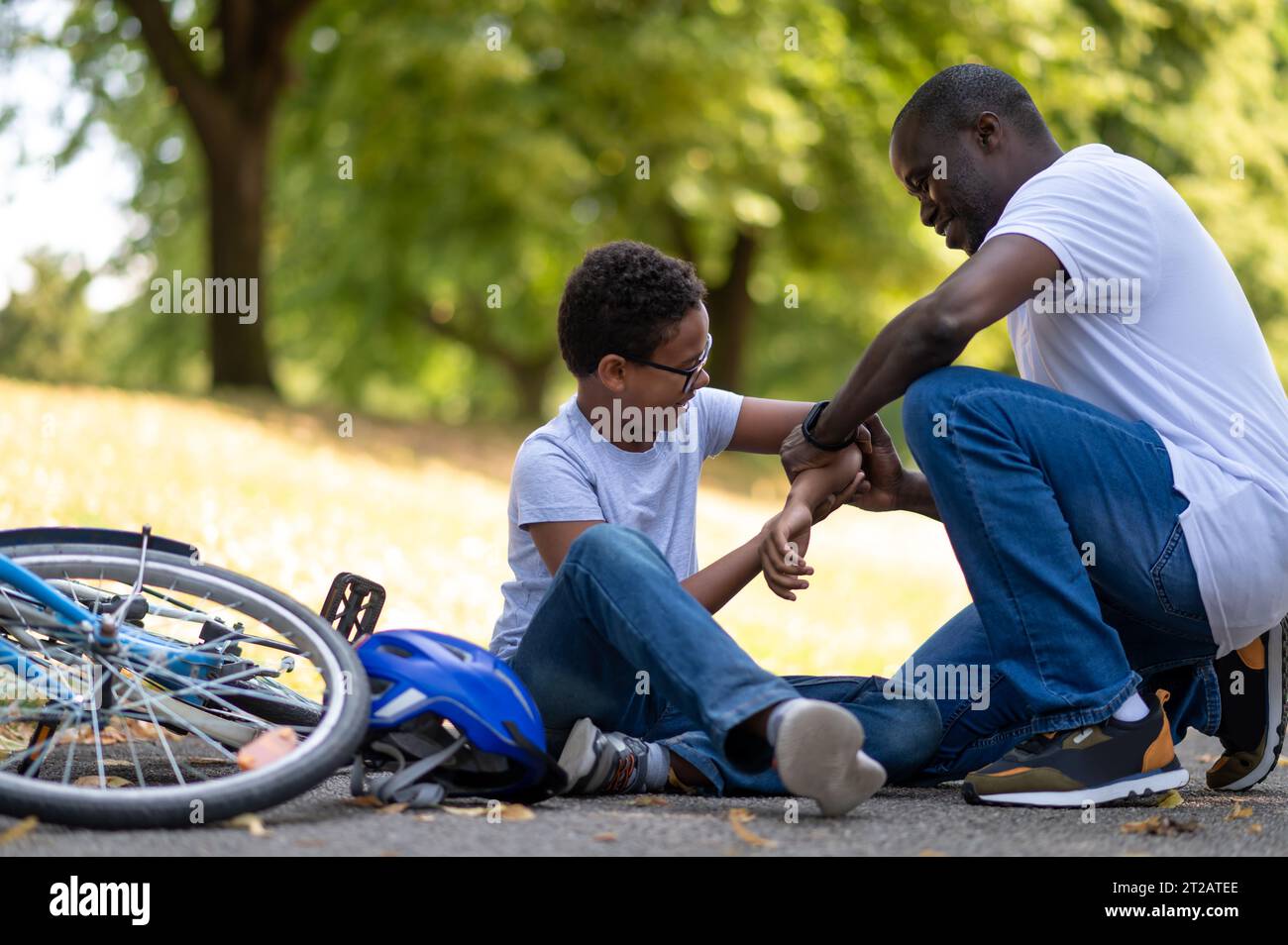 Father helping his kid after falling from the bike Stock Photo