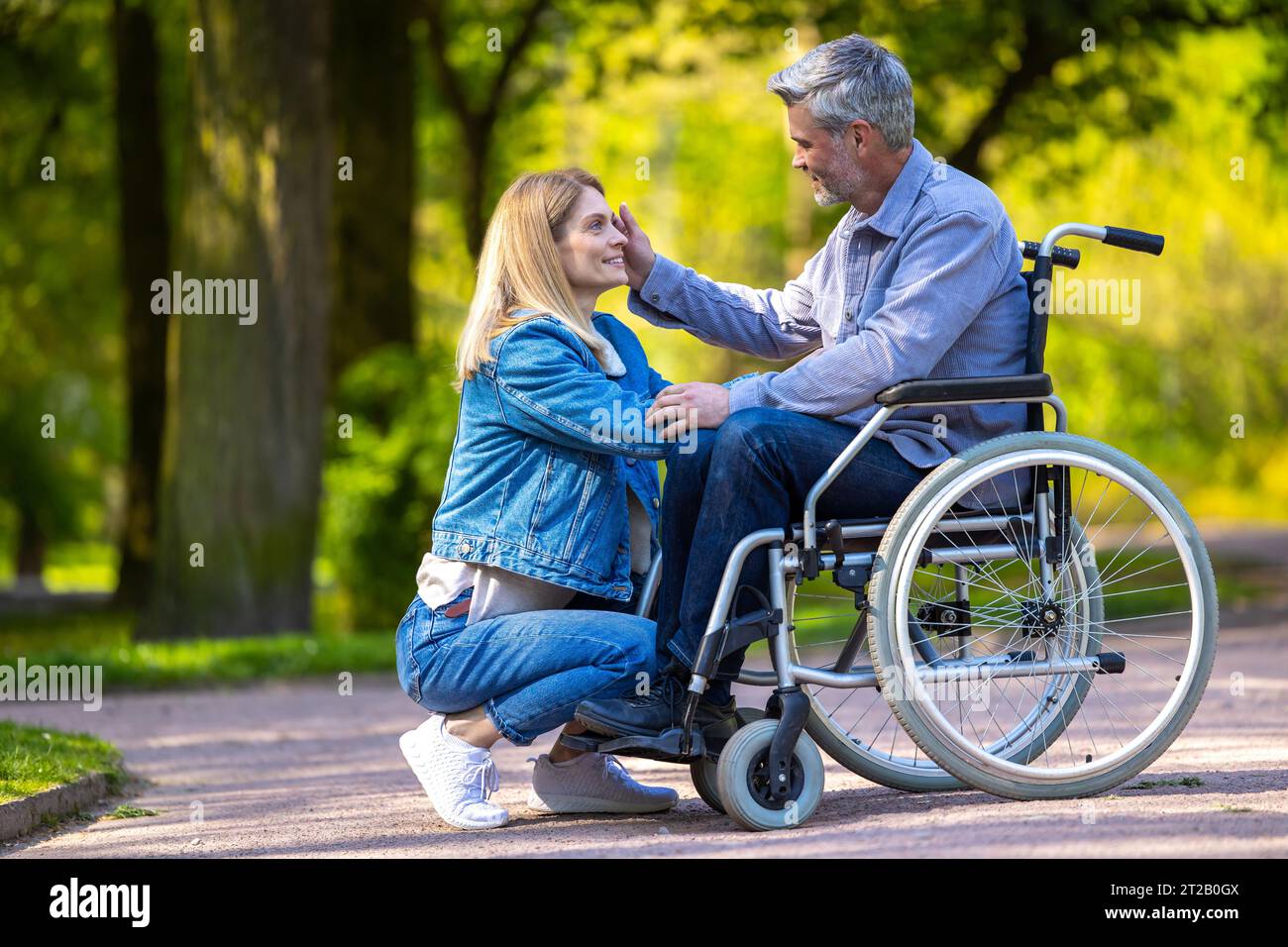 Man on a wheelchair having a walk in the park with his wife Stock Photo ...