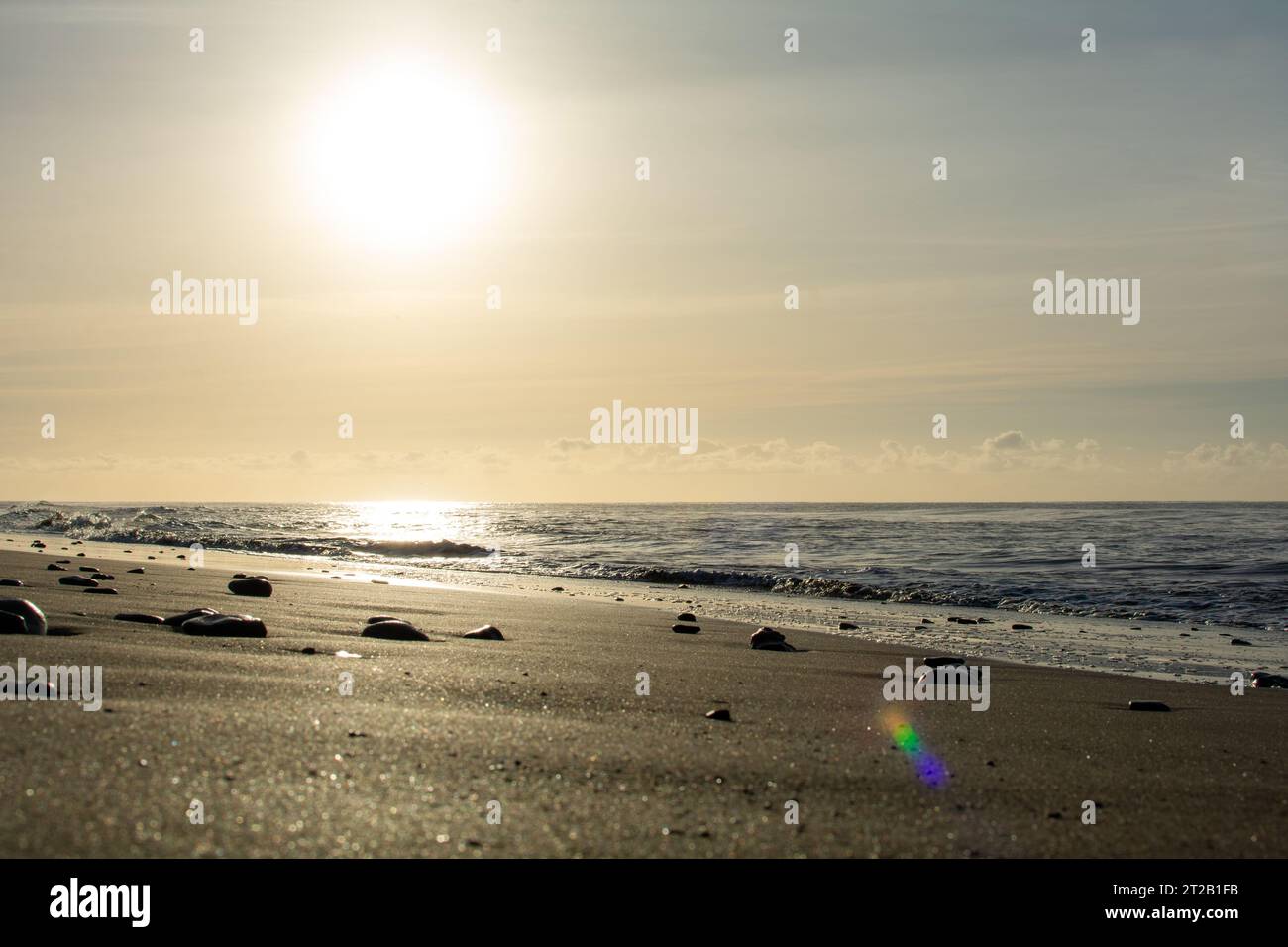 Sunrise on the sea around a sandy beach Stock Photo - Alamy