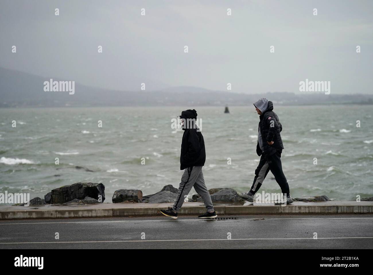 People walk along the seafront in Carlingford, Co. Louth as storm Babet will bring heavy rain to
