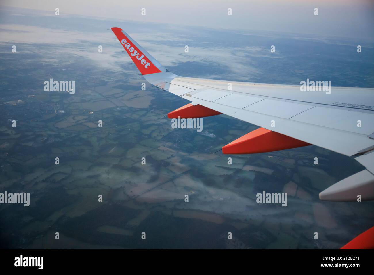 The wing tip of easyJet plane over a view of misty fields in the early ...