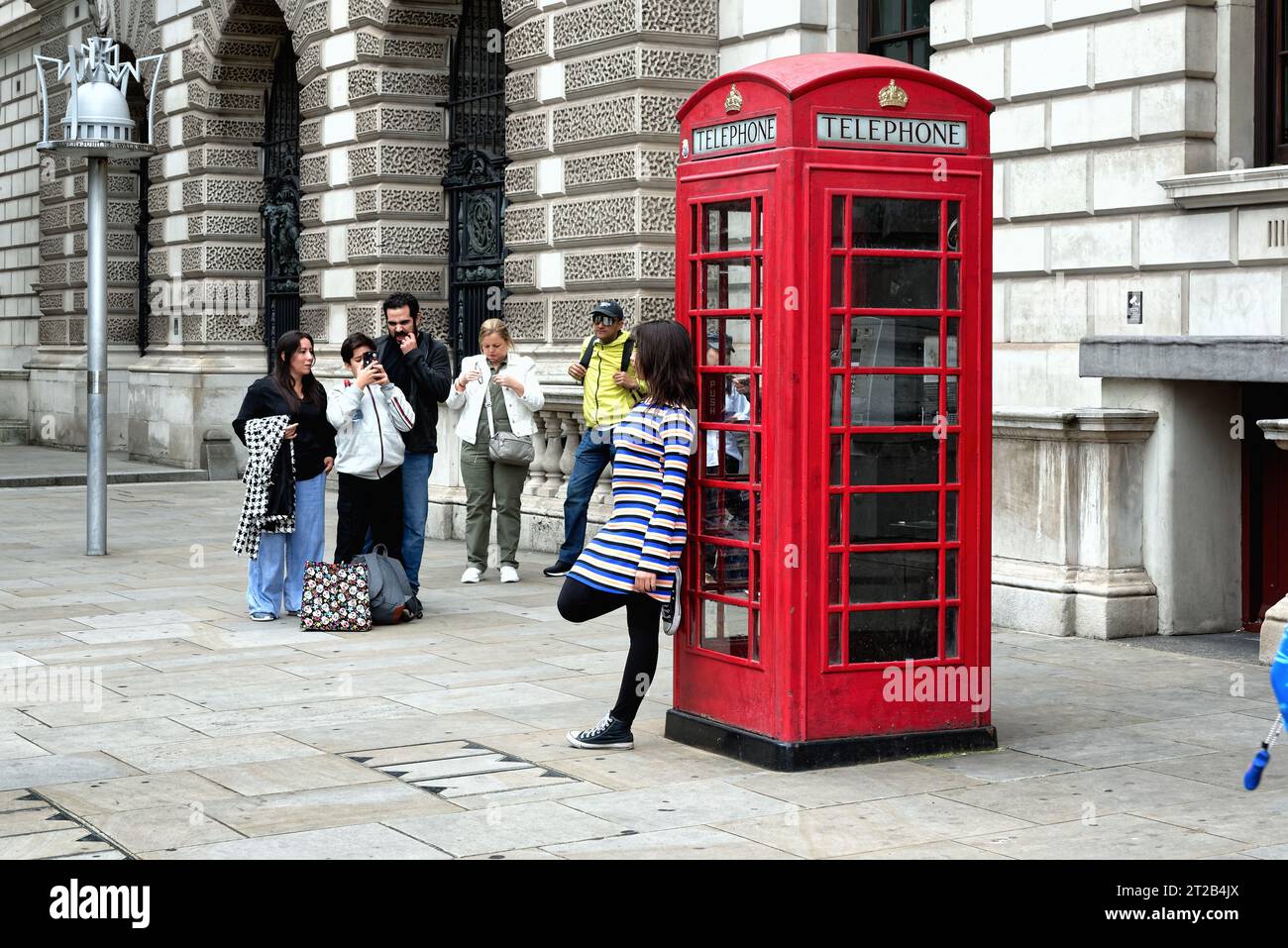 A group of Asians tourists taking photographs by an iconic British red telephone box in Parliament Square Central London England UK Stock Photo