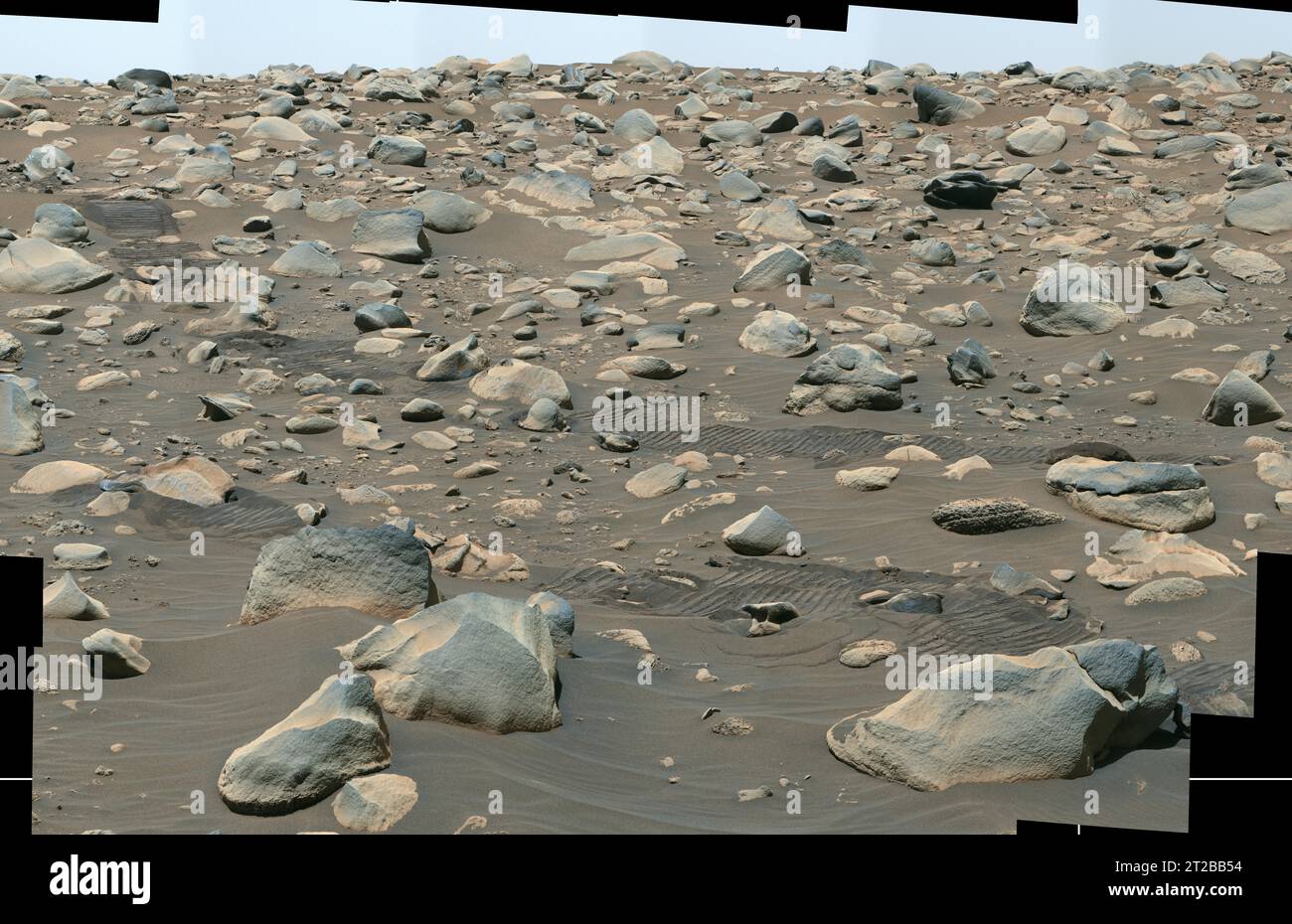 . Perseverance Views Jezero Boulder Field. This composite image captured by NASA's Perseverance Mars rover shows boulders that decorate the top of the Jezero Crater fan deposit. Rover tracks across the middle of the image give a sense of scale. These boulders were transported by water that was either deeper or flowed faster than the ancient waterway that deposited the smaller pebbles that also populate the area. Because these boulders are sitting on top of the pebbles, scientists believe they arrived later, possibly much later. Perseverance's Mastcam-Z camera system took the series of images t Stock Photo