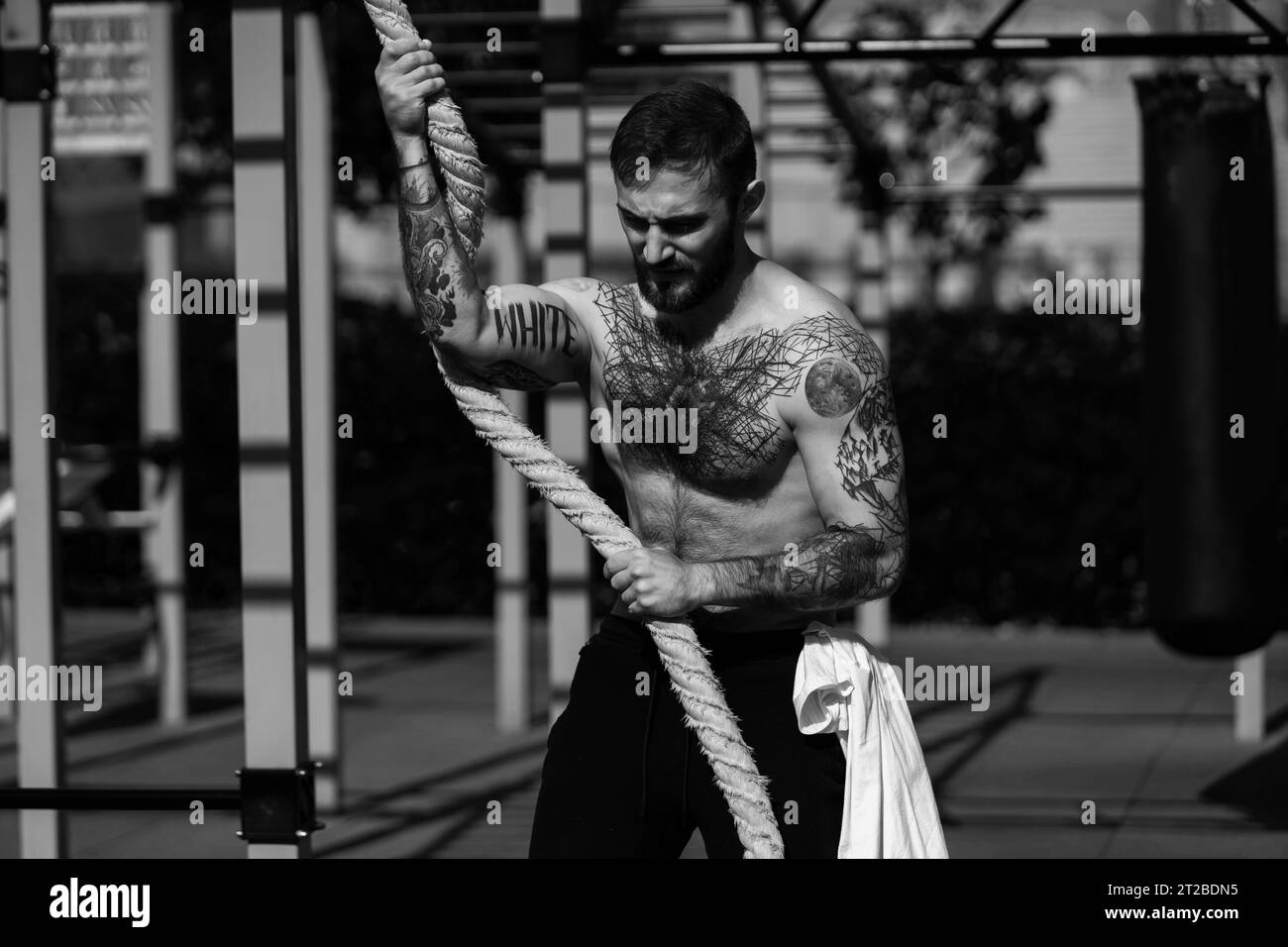 Muscular handsome man is training upper body on machines on street sports ground in city centre. Stock Photo