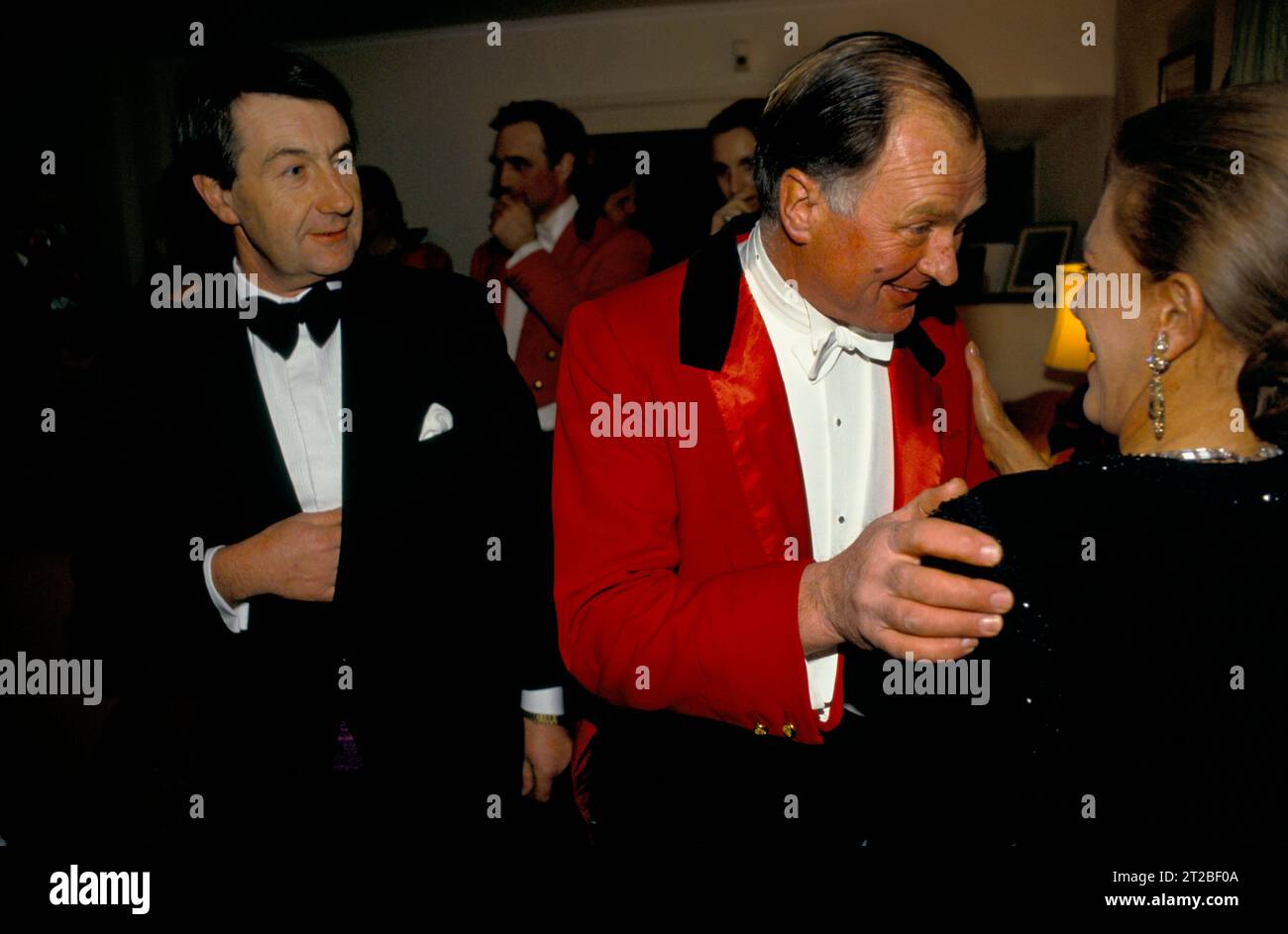 Master of the Foxhounds in traditional Hunting pink chatting up a woman at the Hunt Ball at Tysoe Manor, celebrates the end of the hunting season. Tysoe, Warwickshire, England April 1982. 1980s UK HOMER SYKES. Stock Photo
