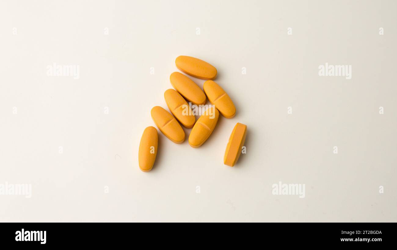 Multivitamin supplement pills set against a neutral off-white backdrop. Stock Photo