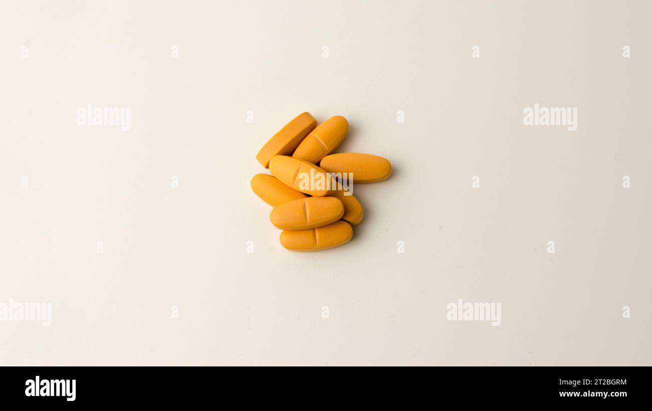 Multivitamin supplement pills set against a neutral off-white backdrop. Stock Photo