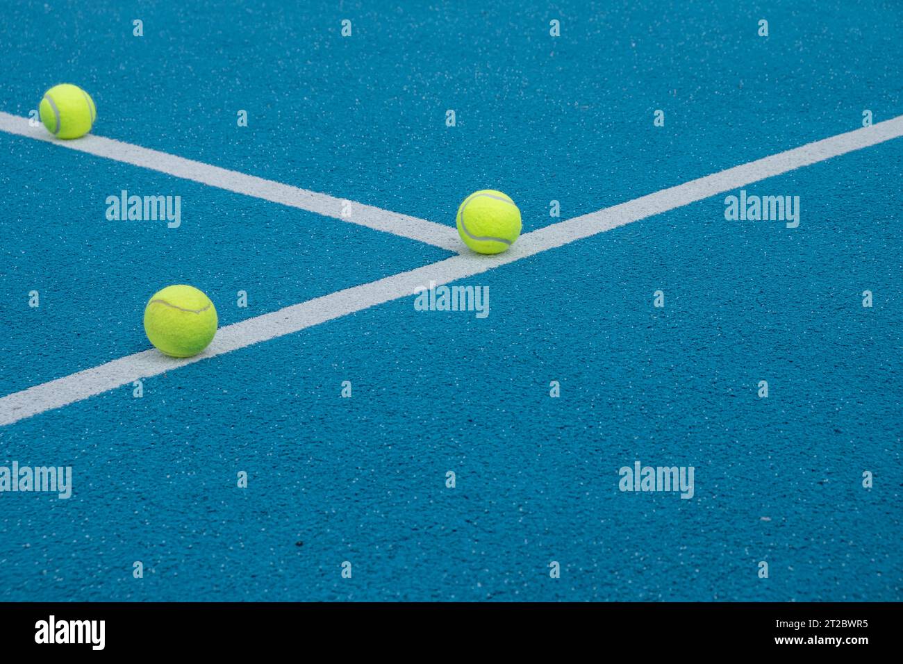 three balls on the lines of a blue paddle tennis court, racket sports concept Stock Photo