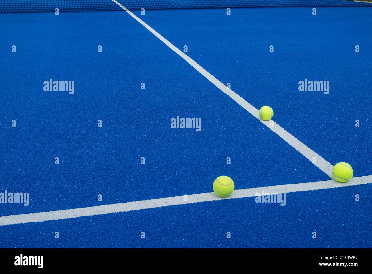 three balls on the lines of a blue paddle tennis court Stock Photo